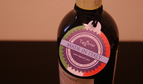 Un cartellino intelligente di Tag Over, con chip NFC integrato, applicato a una bottiglia di vino.